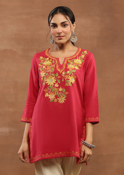 Woman wearing a red embroidered kurta against a brown background